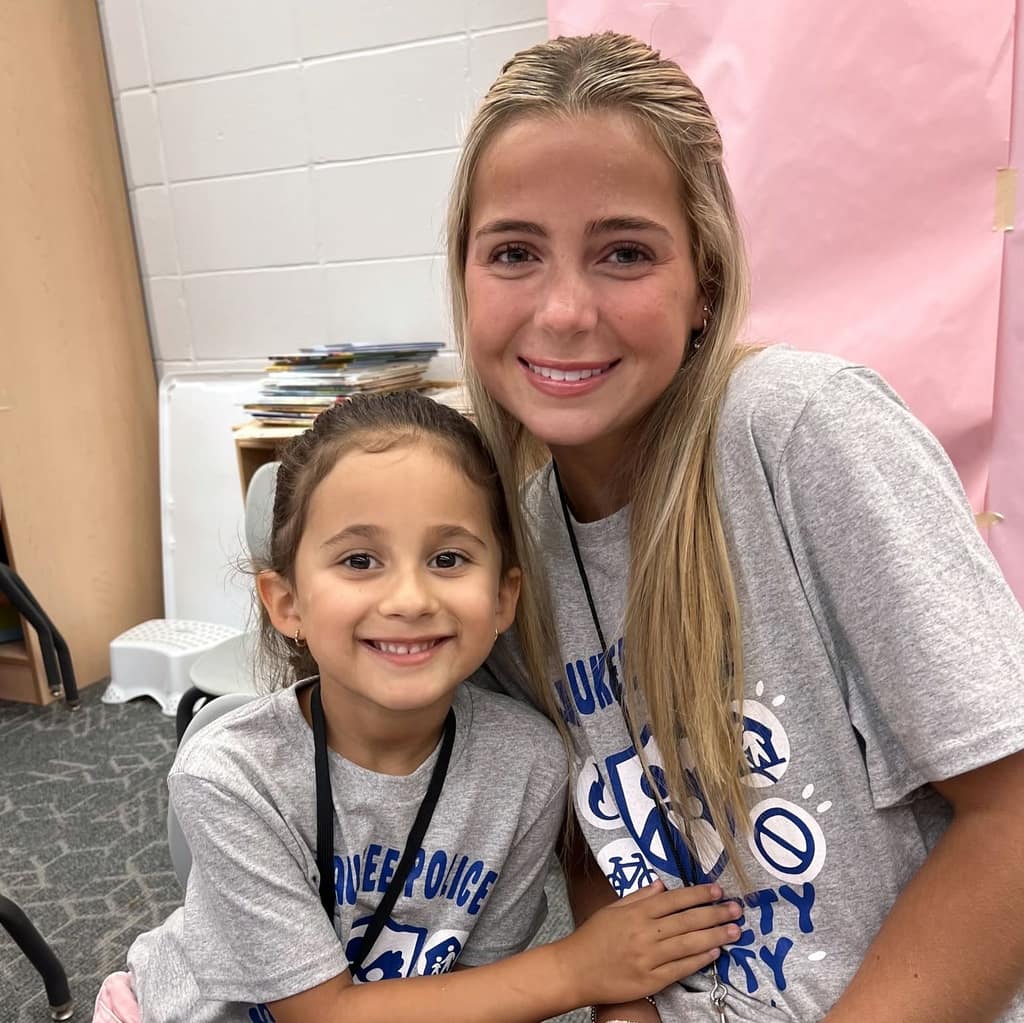 A high school student poses with a young student at an event