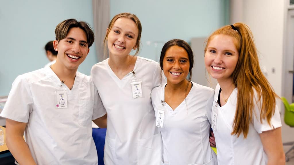 Four Waukee APEX students in scrubs