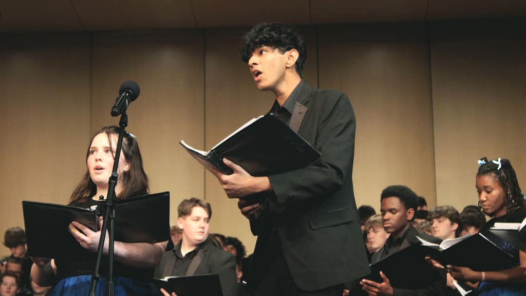 Waukee choir students rehearsing with music folders