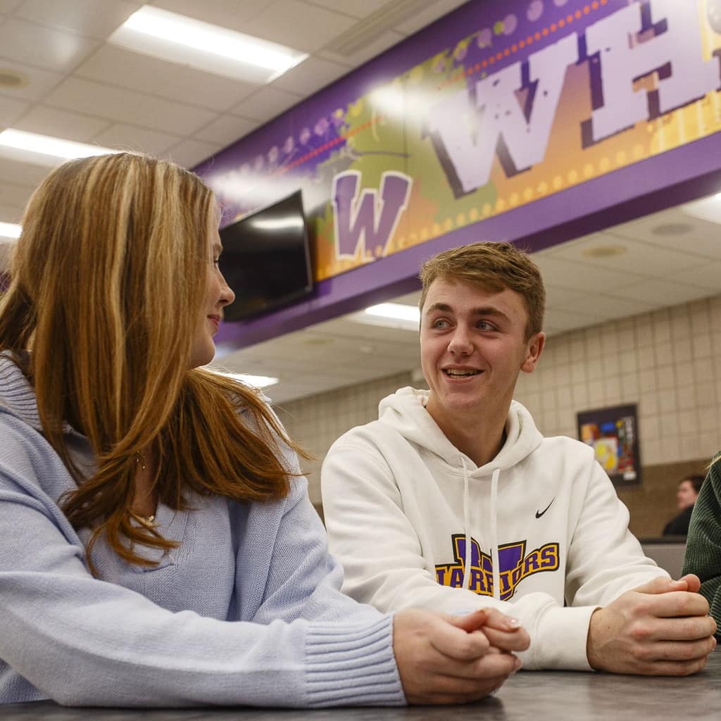 Two students talking at a lunch table